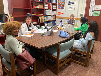 Students and college admissions counselors seated around a conference table working on college applications. 