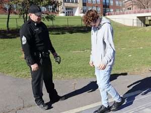 A student wearing fatal vision goggles walks a straight line as an Albany County Stop DWI officer stands nearby.