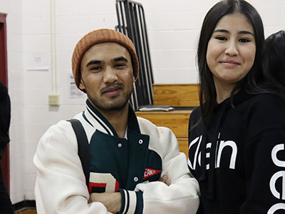 Two English languages learners stand next to each other looking and smiling at the camera.