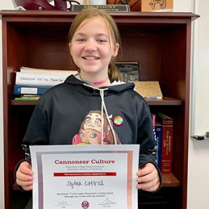Grade 7 Cannoneer Culture "Be Proud" Student of the Month for October 2022 holding award certificate and smiling at camera.