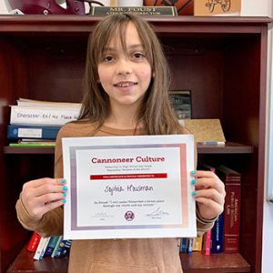 Grade 6 Cannoneer Culture "Be Proud" Student of the Month for October 2022 holding award certificate and smiling at camera.