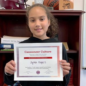 Grade 6 Cannoneer Culture "Be Positive" Student of the Month for October 2022 holding award certificate and smiling at camera.