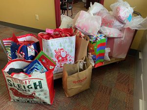 Several bags containing wrapped gifts sit on and around a cart. The gifts were donated by teachers and staff to be given to local families for the holidays.