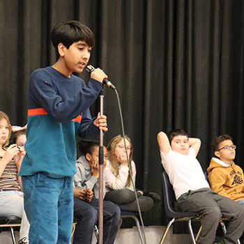 The spelling bee champ stands at the microphone during the competition.