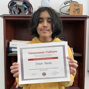 Grade 7 Student of the Month smiles at camera while holding Cannoneer Club Award Certificate
