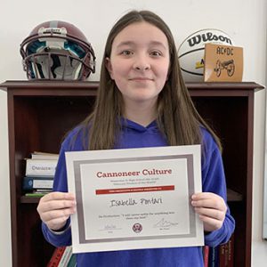 Grade 8 Student of the Month smiles at camera while holding Cannoneer Club Award Certificate