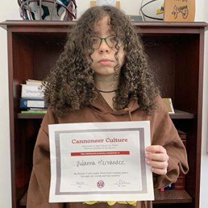 Grade 7 Student of the Month smiles at camera while holding Cannoneer Club Award Certificate