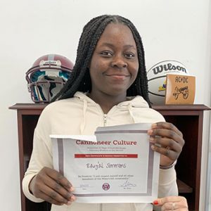 Grade 8 Student of the Month smiles at camera while holding Cannoneer Club Award Certificate