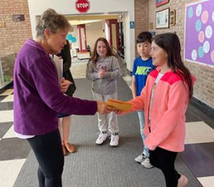 Elks officer greets essay winner and hands the student a prize.