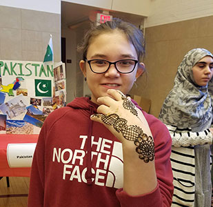 Student with henna tattoo on back of hand smiles at camera