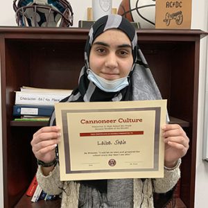 Grade 8 Student of the Month smiles at camera while holding Cannoneer Culture award certificate.