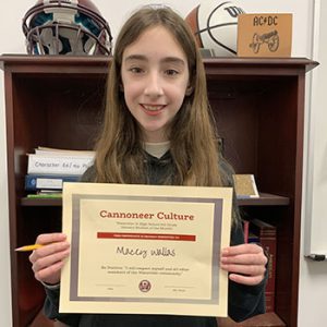 Grade 6 Student of the Month smiles at camera while holding Cannoneer Culture award certificate.