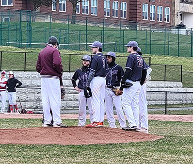 Several Watervliet baseball players gather around the pitching mound.