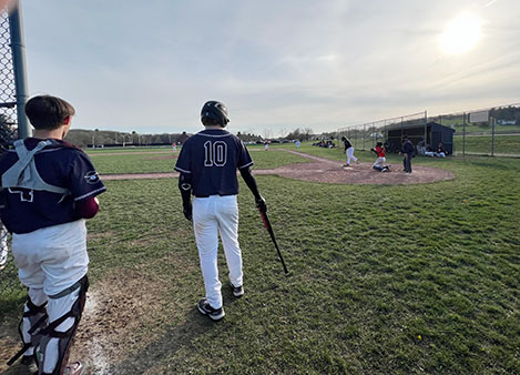 Two Watervliet baseball players standing at the dugout as the sunsets on the field.