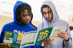 Two students read through a college brochure at the College Caravan