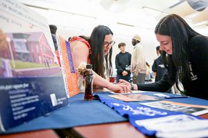 A college admissions representative assists a student filling out an information request form during the college caravan.