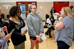 Two students speak with a college admissions rep at the college caravan.