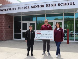 Stewart's Shops manager presents a check to the superintendent and the principal outside the main entrance at Watervliet Junior Senior High School.