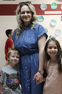 A special person holds hands with two students as they pose smiling for a photo during Special Persons Night at Watervliet Elementary School. 