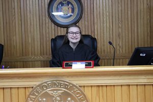 A high school senior dressed in a judge's black robe sits on the judge's bench in Watervliet City Court during the Youth Day job shadow event