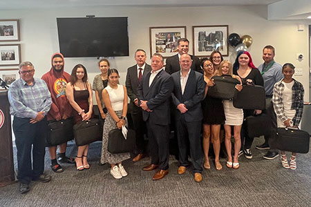 Fifteen college-bound seniors hold  new laptops while standing with Watervliet Housing Authority executive director and a group of local dignitaries