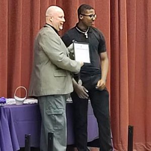 Educator presents National Technical Honor Society certificate to student