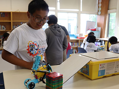 A student watches a robotic vehicle attempt to maneuver over a ramp 