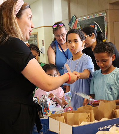 Special Education Director hands out bags of popcorn to students waiting in line