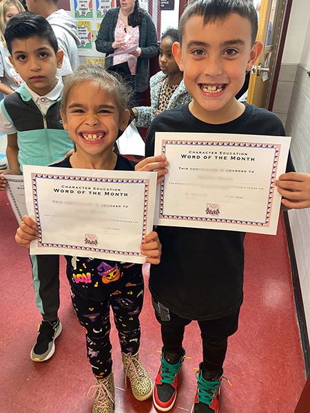Two students hold their award certificates and smile for the camera.