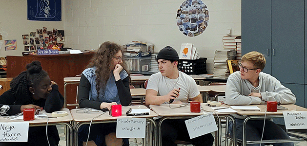 Two members of the Master Minds team collaborate to come up with an answer to a question, while two other team members look on. 