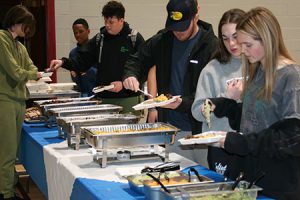 Several students line up at the taco bar for a special lunch in recognition of their academic achievements