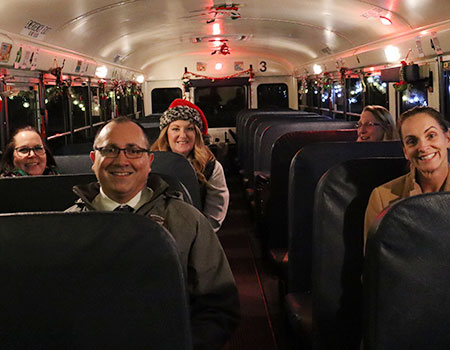 District administrators are joined by staff and board members on a school bus decorated for the holiday parade 