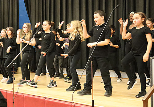 The entire drama club cast performs the Zombie dance on stage 