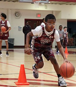 CYO player practices dribbling the ball down the court through a row of orange cones