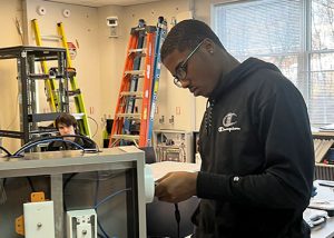 Students threads a cable through a box