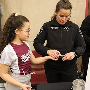 A sheriff's deputy places a student's finger in a fingerprint processor for a photo ID