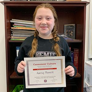 Be Positive grade 6 student of the month holds award certificate and smiles at camera