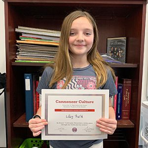 Be Proud grade 6 student of the month holds award certificate and smiles at camera