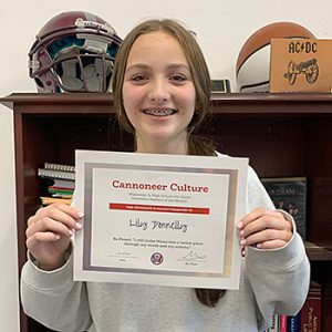 Be Proud grade 8 student of the month holds award certificate and smiles at camera