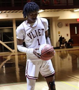 Watervliet basketball player holds and looks down at commemorative basketball in his hands