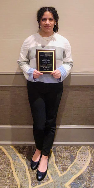 Watervliet High School senior looks at camera while holding holding award