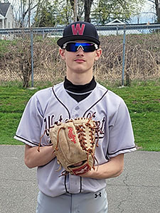 Varsity baseball player in uniform with ball in glove