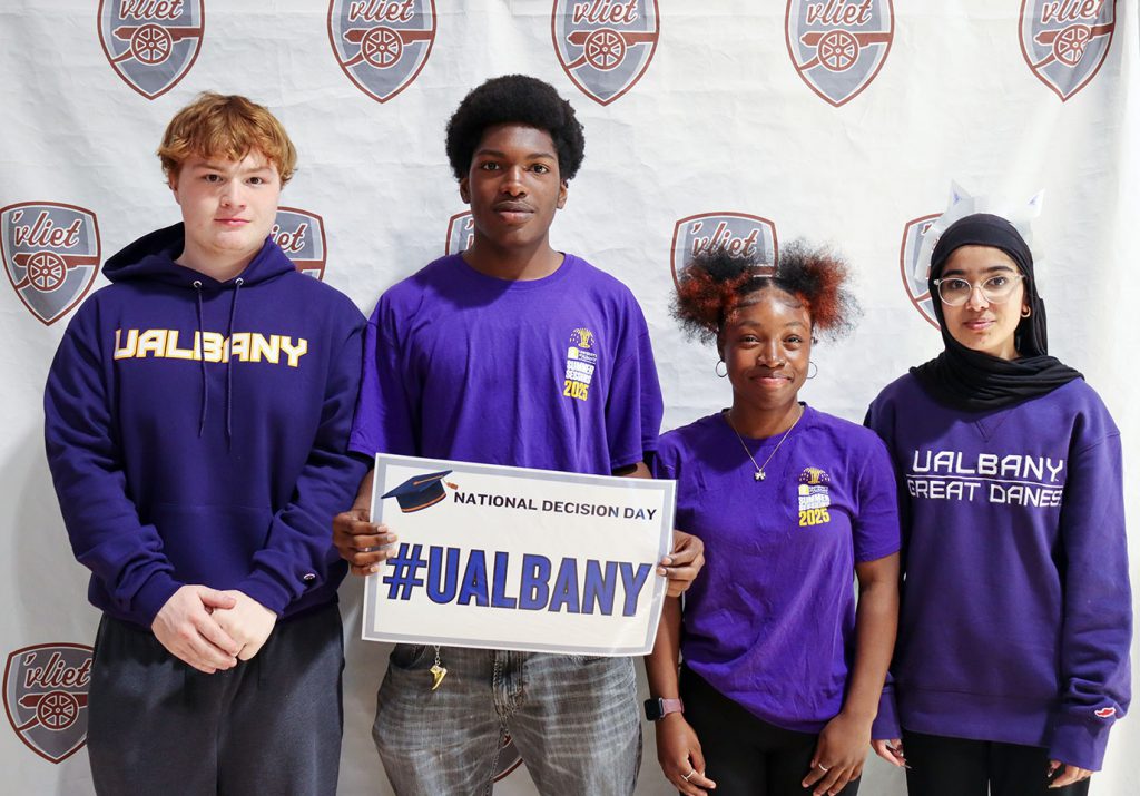 Four members of the Class of 2025 hold a U Albany sign and smile 