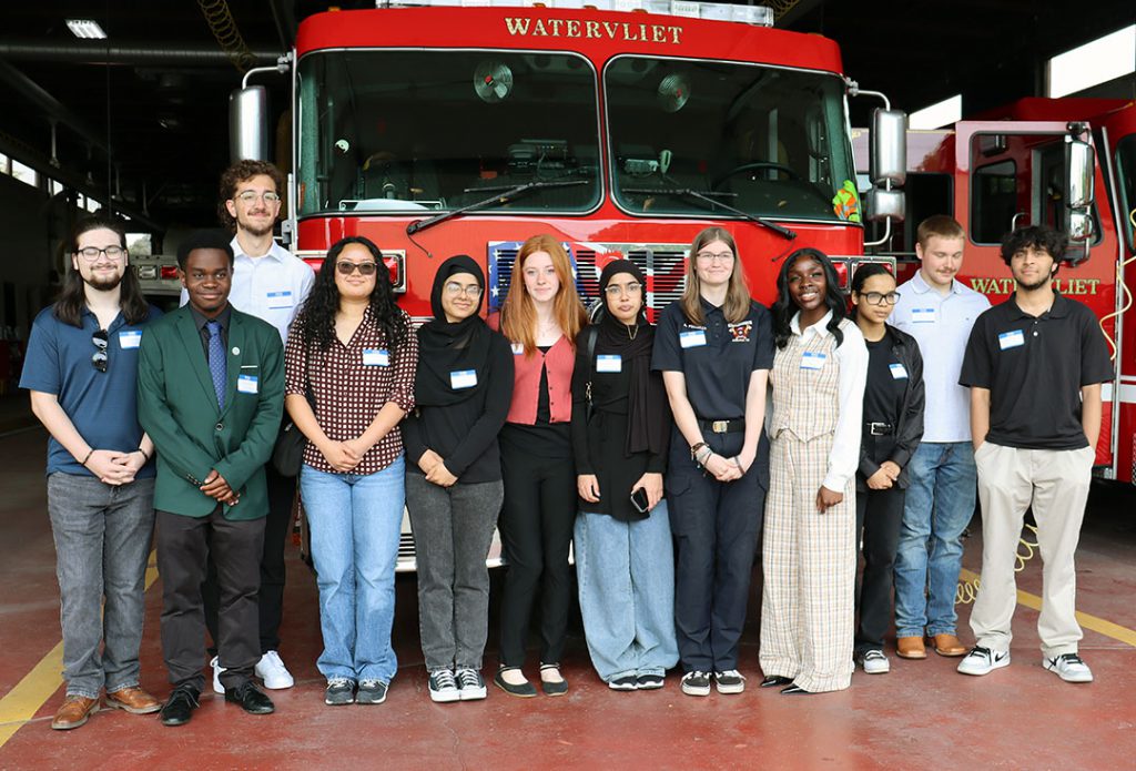 Approximately one dozen high school seniors stand together in front of a fire engine at the Watervliet Fire Department 