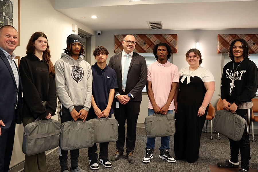 Five Watervliet High School seniors hold new laptops as they stand with the superintendent, Watervliet Housing Authority Executive Director and RPI graduate who is a Watervliet alum