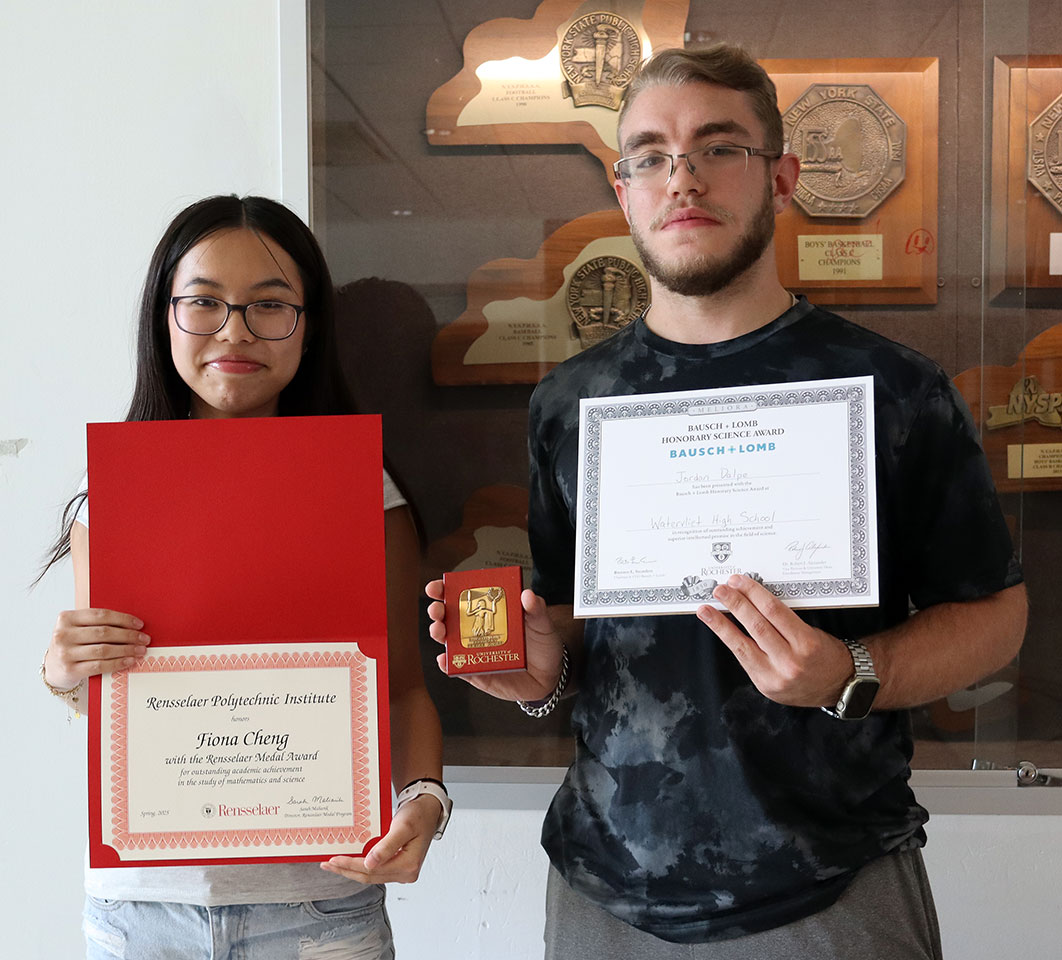 Two high school juniors smile as they hold scholarship award certificates