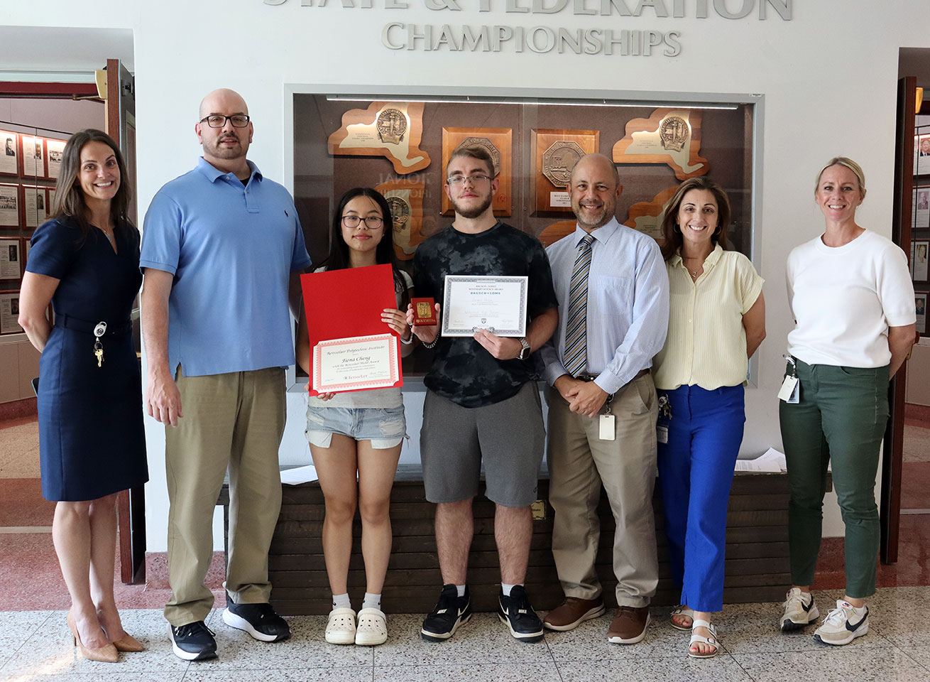 School counselors, principal, teacher and assistant superintendent stand with students receiving scholarship awards