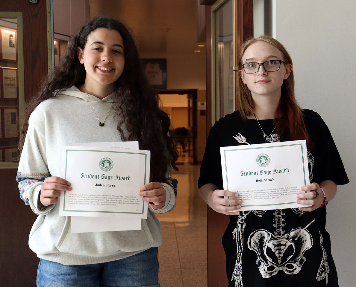 Two high school juniors hold scholarship certificates and smile