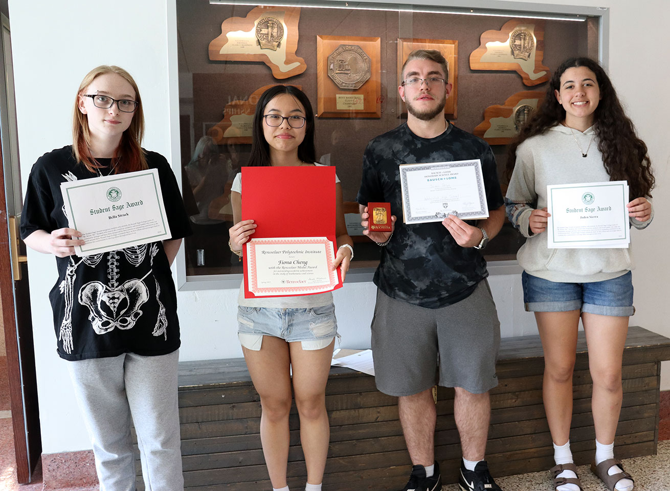 Four students stand together holding scholarship award certificates
