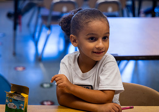 A young student sots at a desk holding a crayon at Watervliet Elementary School